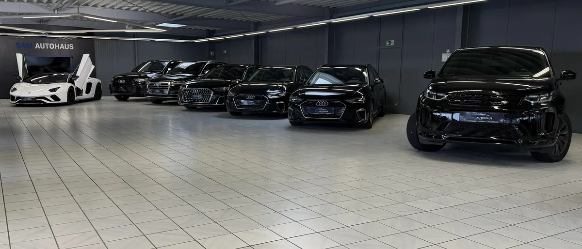 Reihe schwarzer Audi und ein Range Rover im Showroom von SAM Autohaus