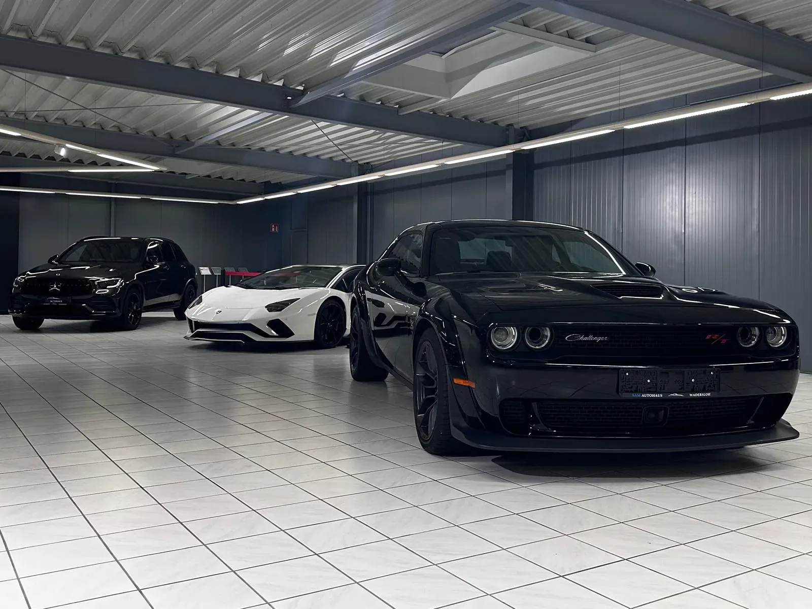 Showroom von SAM Autohaus mit Lamborghini, Dodge Challenger und weiteren Fahrzeugen